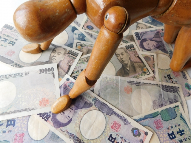 お金の上でうなだれる。京丹後市で借金返済の無料相談ができます